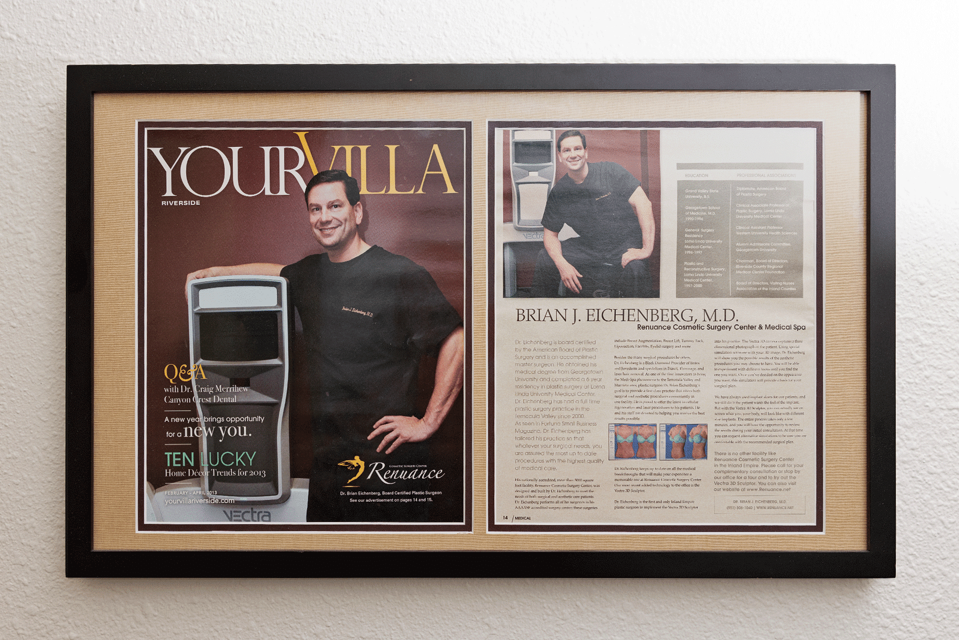 A framed display of a magazine feature. The left side of the frame shows a cover of "Your Villa" magazine with the image of a man posing next to a machine and the headline "Q&A with Dr. Ailen Taylor". The right side is an article about Brian J. Eichenberg, M.D., featuring another image of the same man sitting on a table wearing black scrubs and smiling. The text discusses his work in reconstructive and cosmetic surgery.
